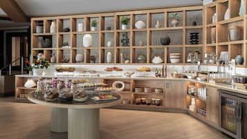 Une cuisine moderne avec des meubles en bois, un îlot central où sont exposés des aliments, ainsi qu’une variété d’ustensiles de cuisine et d’objets décoratifs disposés sur des étagères.