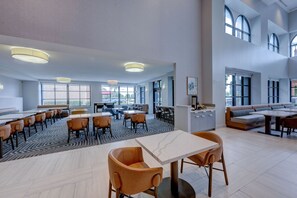 A spacious dining area with high ceilings, large windows, and modern furnishings.