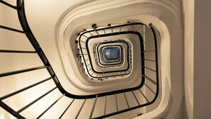 Una escalera en espiral con un panel de vidrio central y barandillas metálicas.