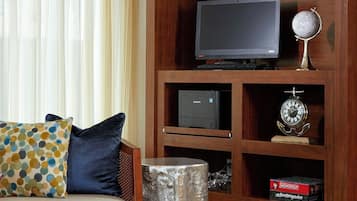 Una sala de estar con sofá, mesa de centro, televisor y estantería con objetos decorativos.