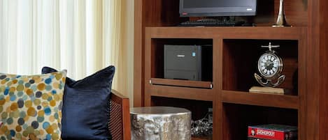 A living room with a sofa, a coffee table, a TV, and a bookshelf with decorative items.