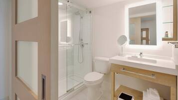 A modern bathroom with a glass-enclosed shower, a toilet, a sink with a mirror, and a towel rack.