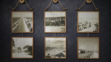 Six black and white photographs of beach scenes, each framed and hung on a dark wall.