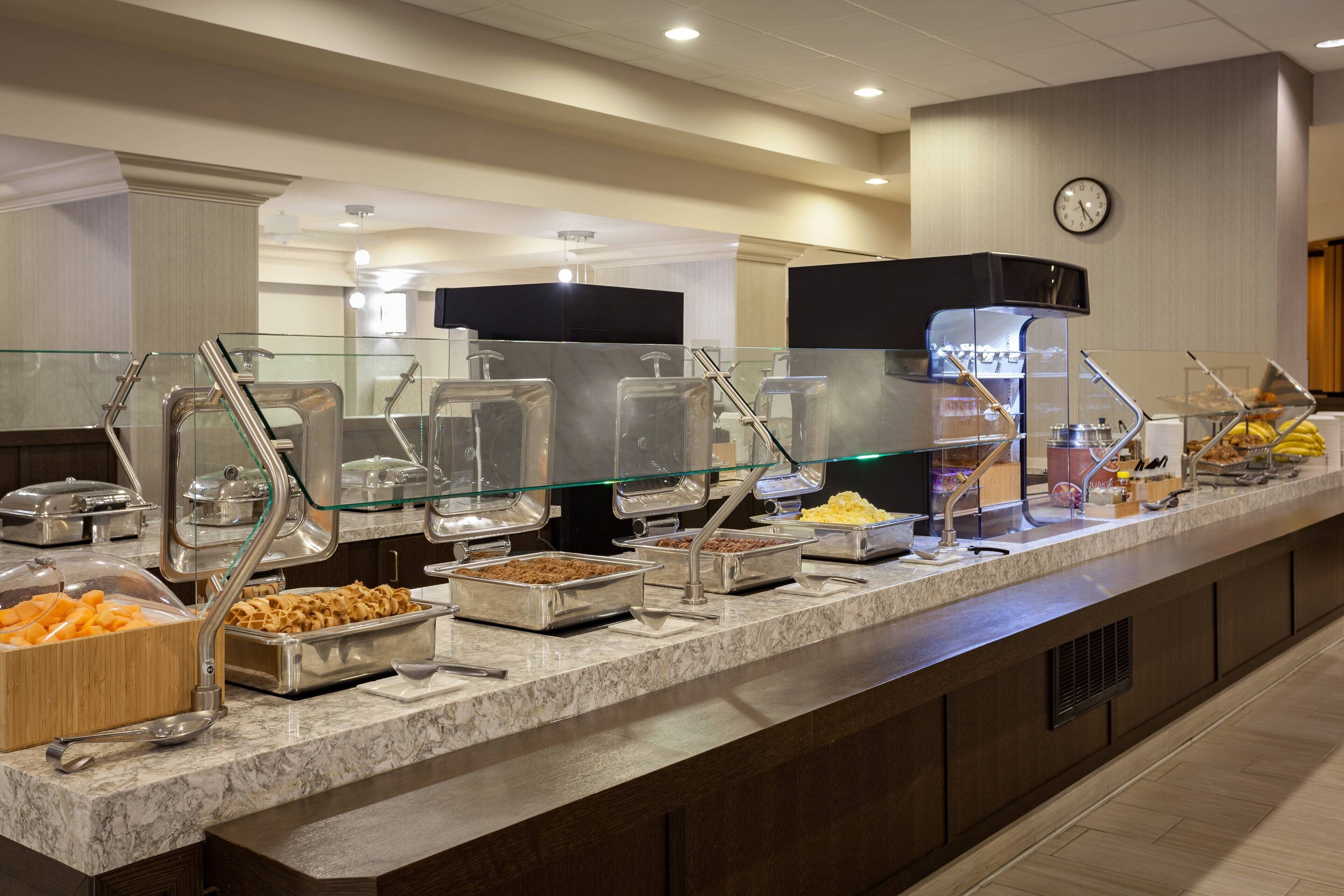 A buffet setup with various food items and a clock on the wall.