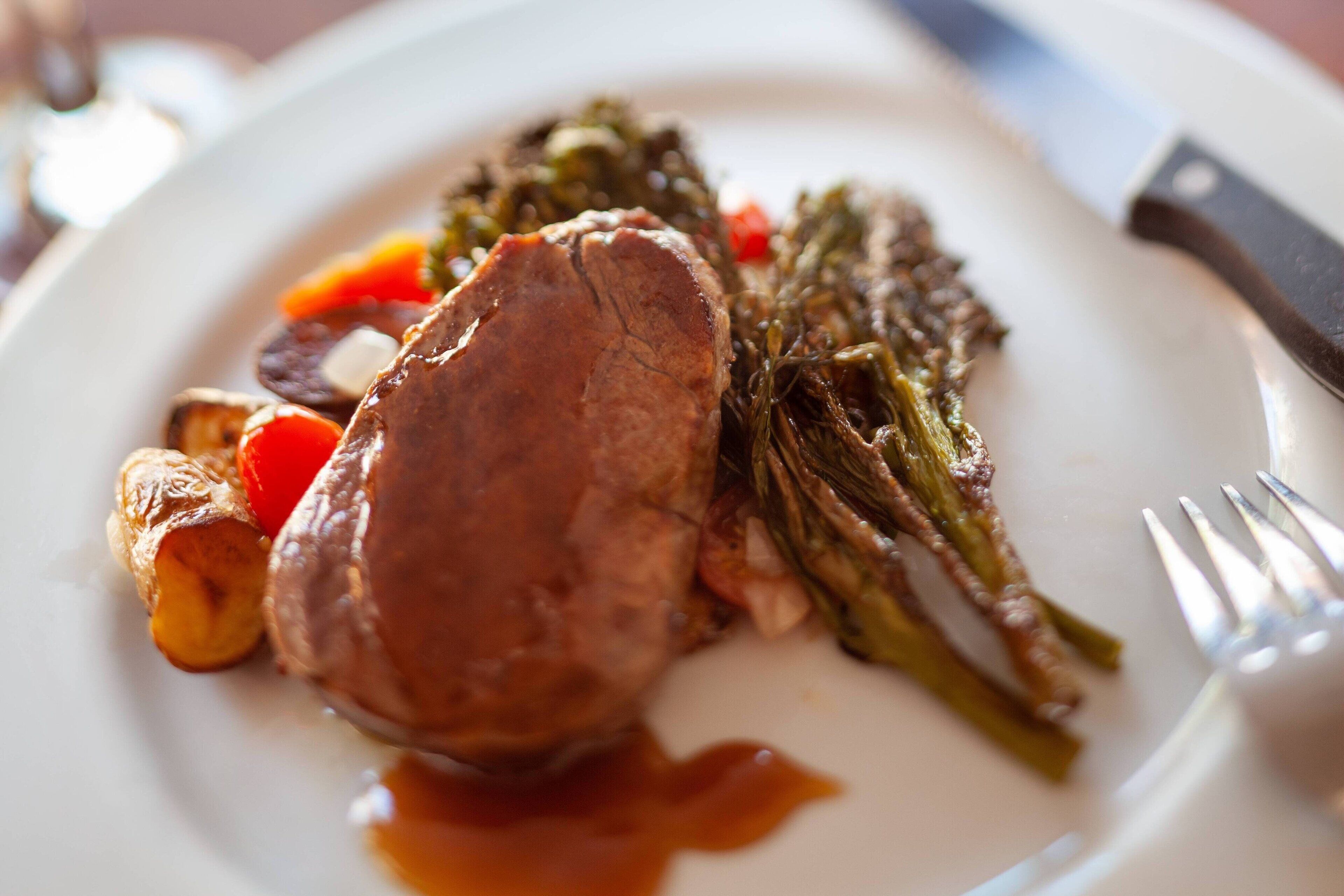 A plate with a piece of meat, vegetables, and sauce.