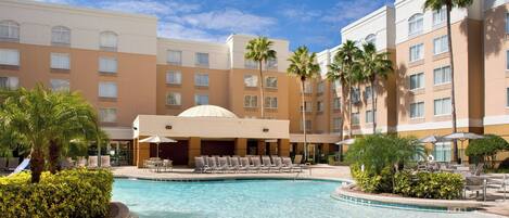 A hotel pool area with lounge chairs and palm trees.