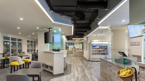 A modern restaurant with a bar area, seating, and a digital menu display. - SpringHill Suites Orlando Lake Buena Vista Marriott Village (Orlando)