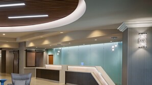 Un'area reception moderna con soffitto curvo, una scrivania reception e zone salotto con poltrone e un piccolo tavolo.