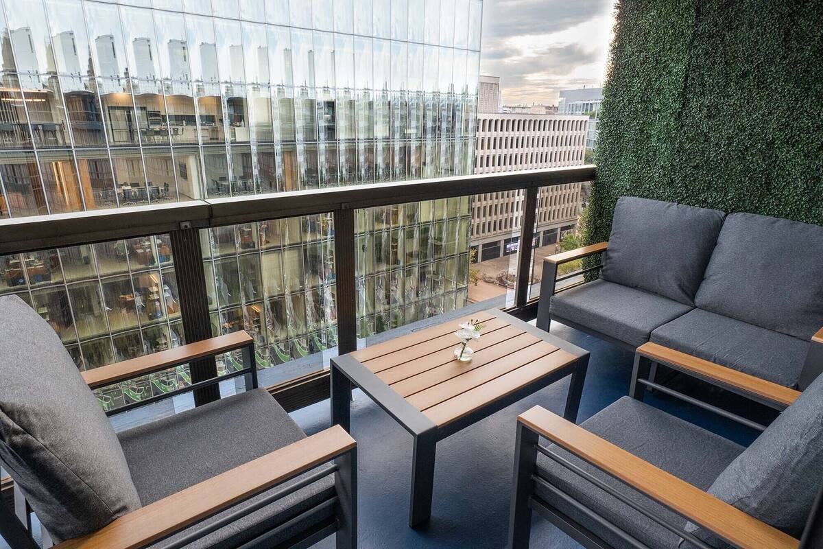 A balcony with a sofa, chairs, and a table.