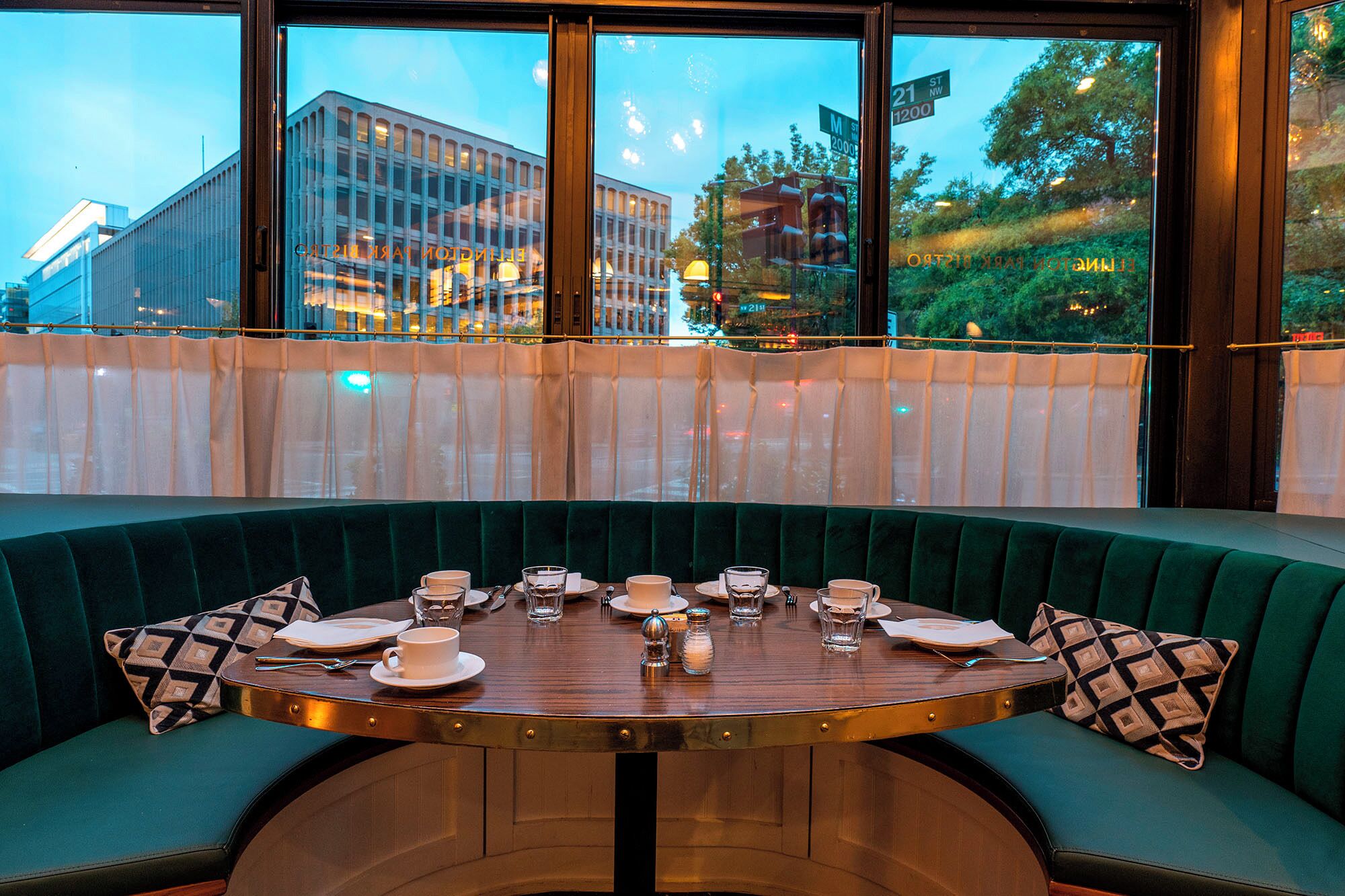 A round table with a wooden top, surrounded by green upholstered seating.