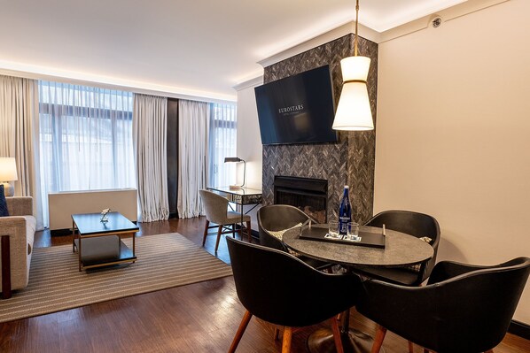 A modern hotel room with a fireplace, a flat-screen TV, a dining area with a round table and chairs, and a sofa. - Eurostars Saint Gregory Dupont Circle Georgetown (Washington)