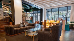 Un hall amplio con diseño moderno, que incluye un sofá, sillones, una mesa de centro y una escalera.