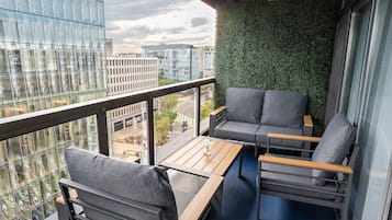 Parveke, josta avautuu näkymä kaupunkiin, viherseinä ja modernit huonekalut.