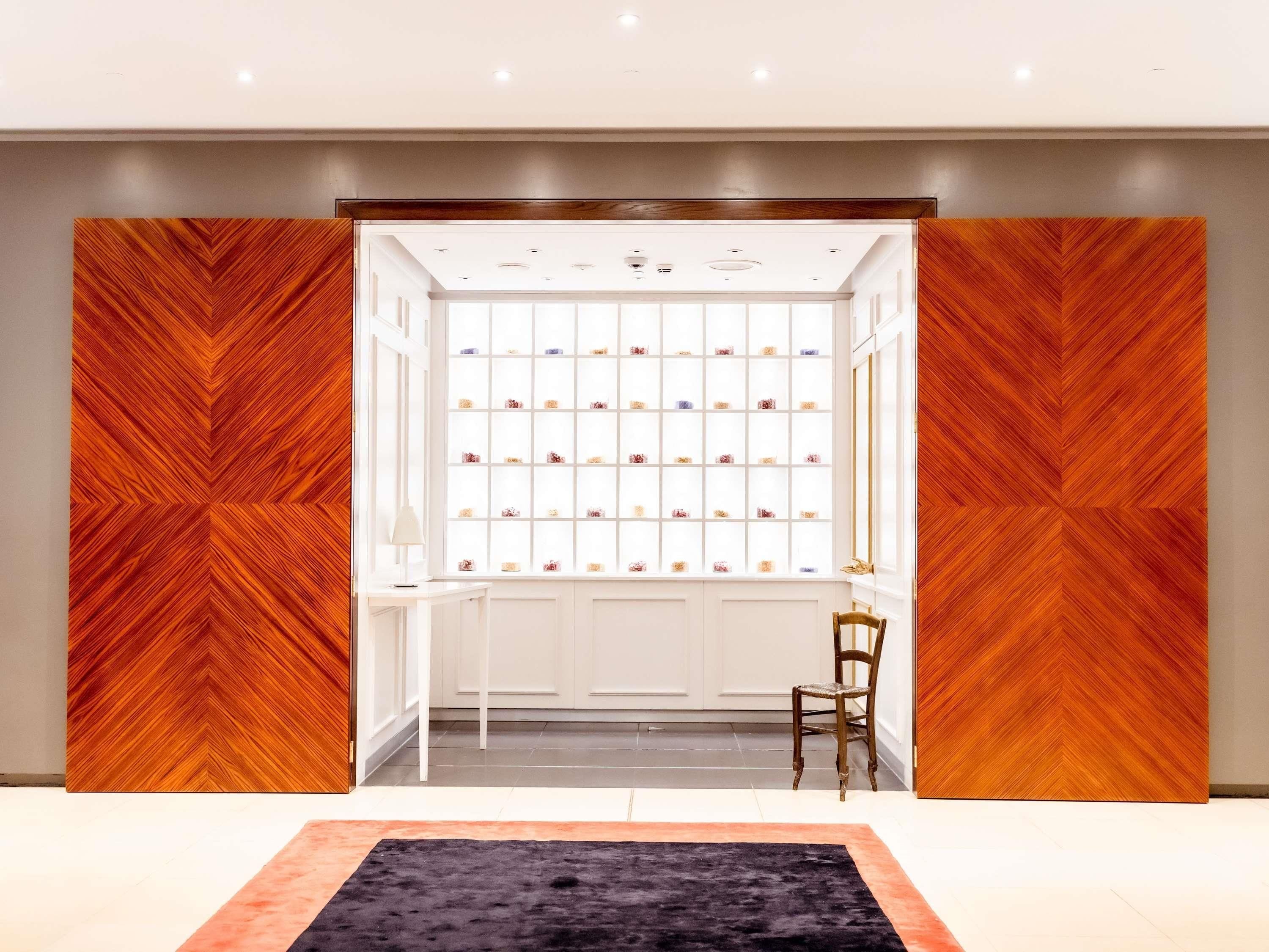 A room with a wooden herringbone wall pattern, a central display of small items, and a chair.