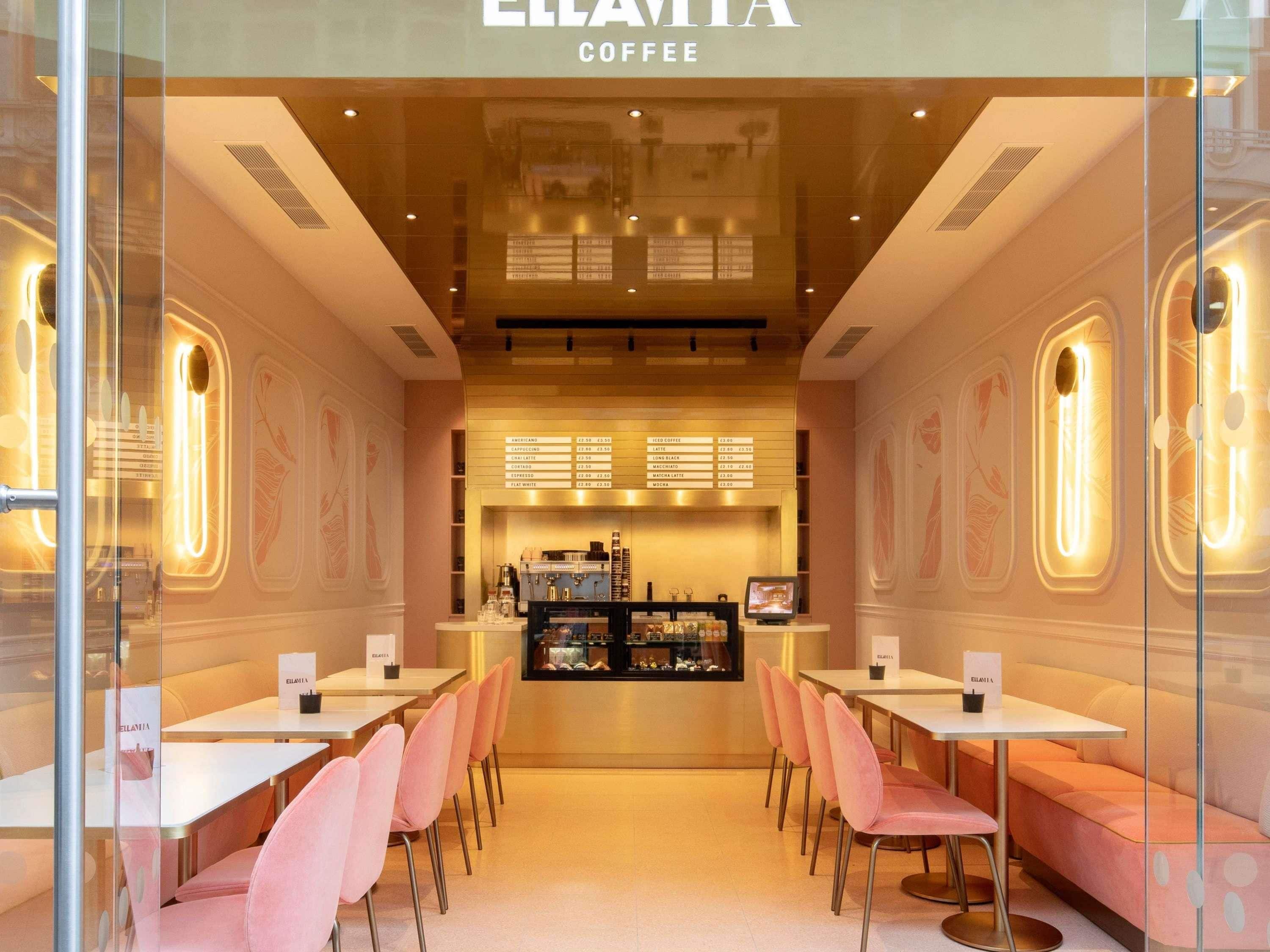A coffee shop interior with tables and chairs, a counter with a menu, and a display case.