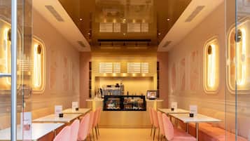 A coffee shop interior with tables and chairs, a counter with a menu, and a display case.