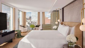 Una habitación de hotel moderna con una cama grande, televisión y vistas a la ciudad.