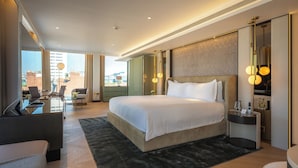 A modern hotel room with a large bed, a desk with a chair, a small table, and a view of the city. - St Martins Lane London, a Morgans Originals hotel (London)