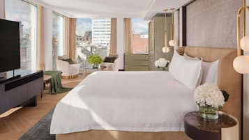 Una habitación de hotel moderna con una cama grande, televisión y vistas a la ciudad.