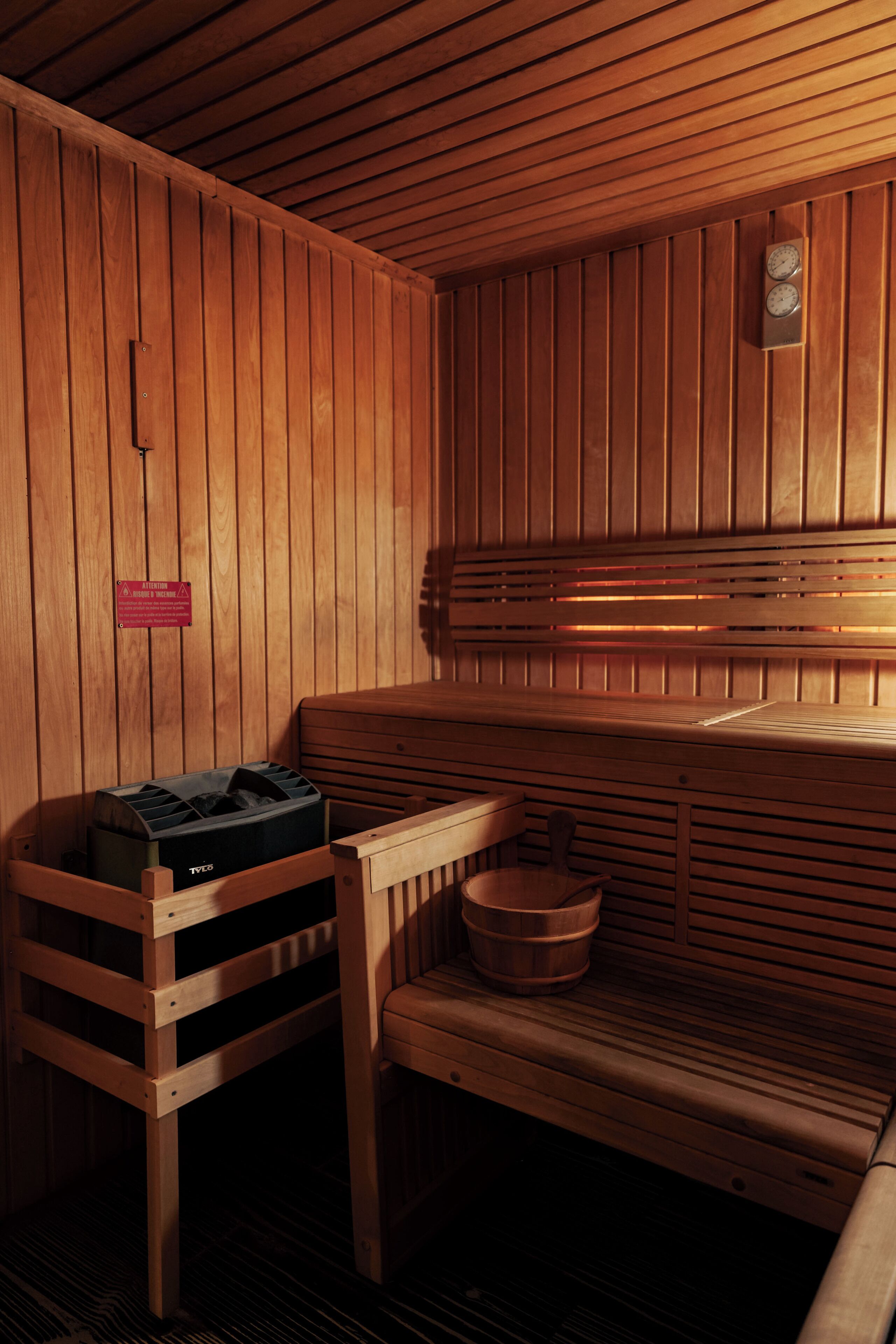 A sauna with wooden benches and a bench with a storage box.