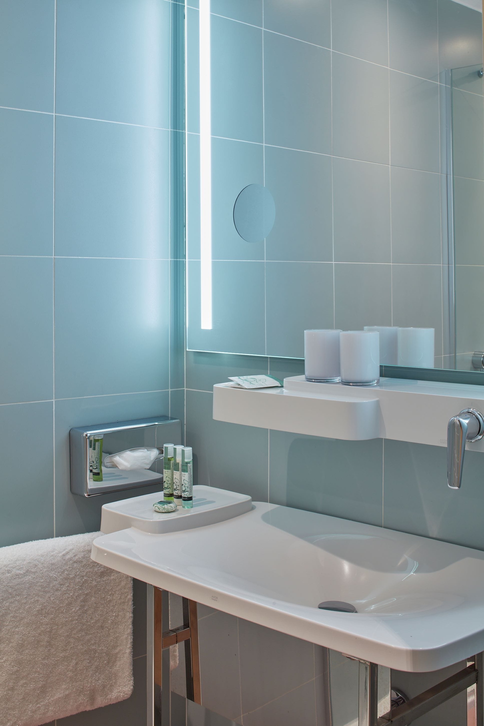 Une salle de bain moderne avec un lavabo blanc, un miroir et un porte-serviettes.