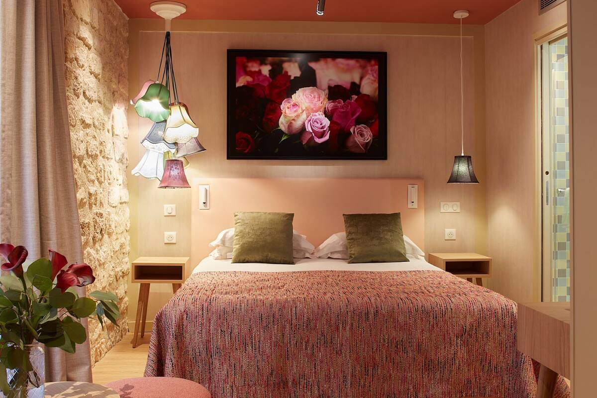 Une chambre à coucher avec un grand lit, deux tables de chevet, un tableau accroché au mur et une fenêtre.