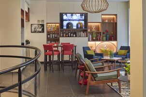 Zona de bar moderna con televisor, taburetes y una variedad de botellas.