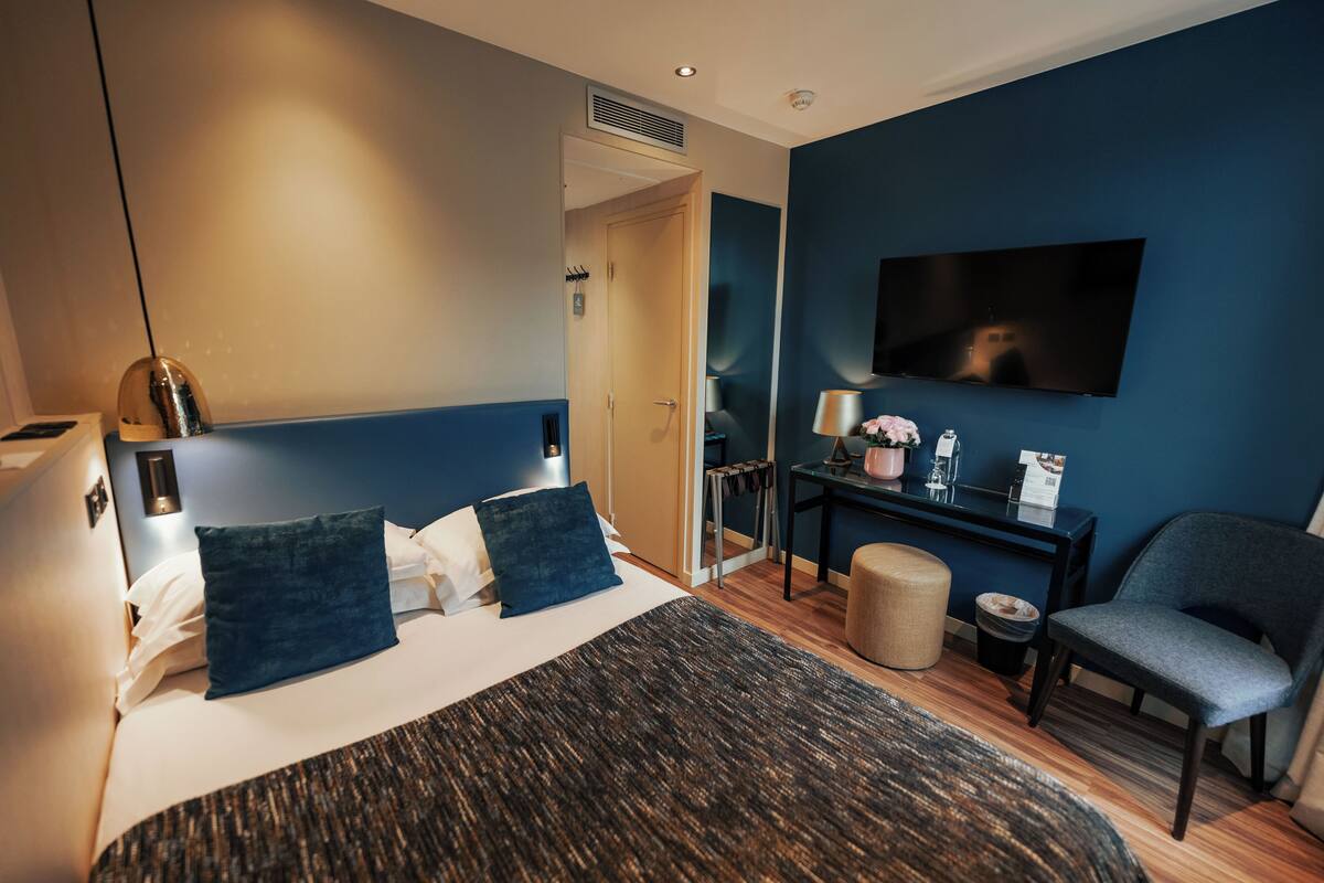 Une chambre d’hôtel moderne équipée d’un lit, d’une table de chevet, d’une télévision et d’un coin salon.