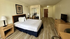 A hotel room with a large bed, bedside tables, a TV, and a mirror. - Closed - Monumental Movieland Hotel (Orlando)