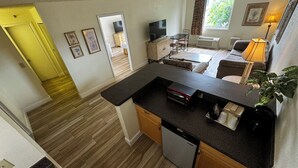 A compact kitchen with a dishwasher, a dining area with a table and chairs, a sofa, and a window with curtains. - Closed - Monumental Movieland Hotel (Orlando)