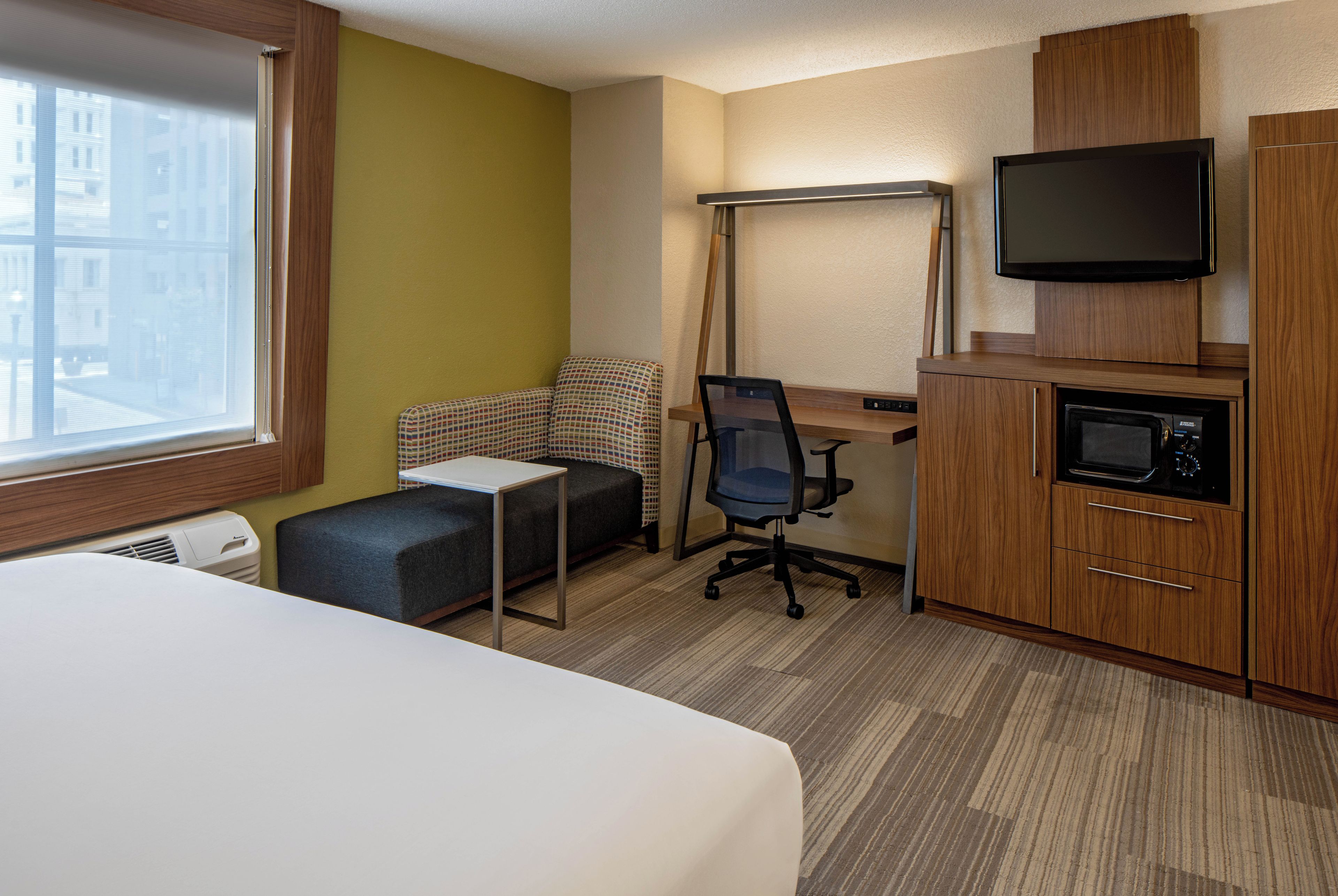 Een hotelkamer met een bed, een bureau, een stoel, een televisie en een magnetron.