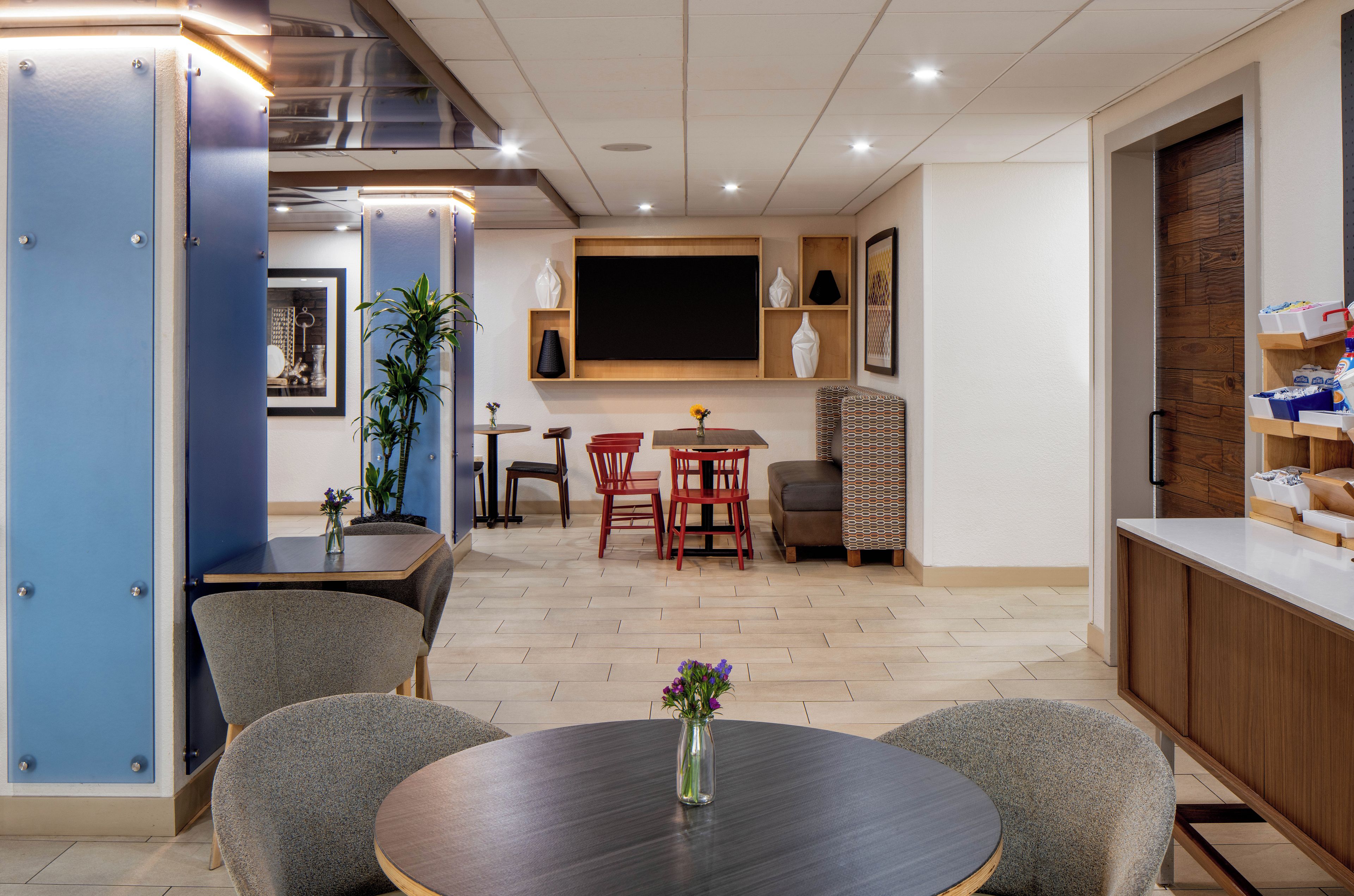 A modern dining area with a round table, chairs, and a television mounted on the wall.
