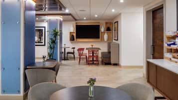Un comedor moderno con una mesa redonda, sillas y un televisor montado en la pared.