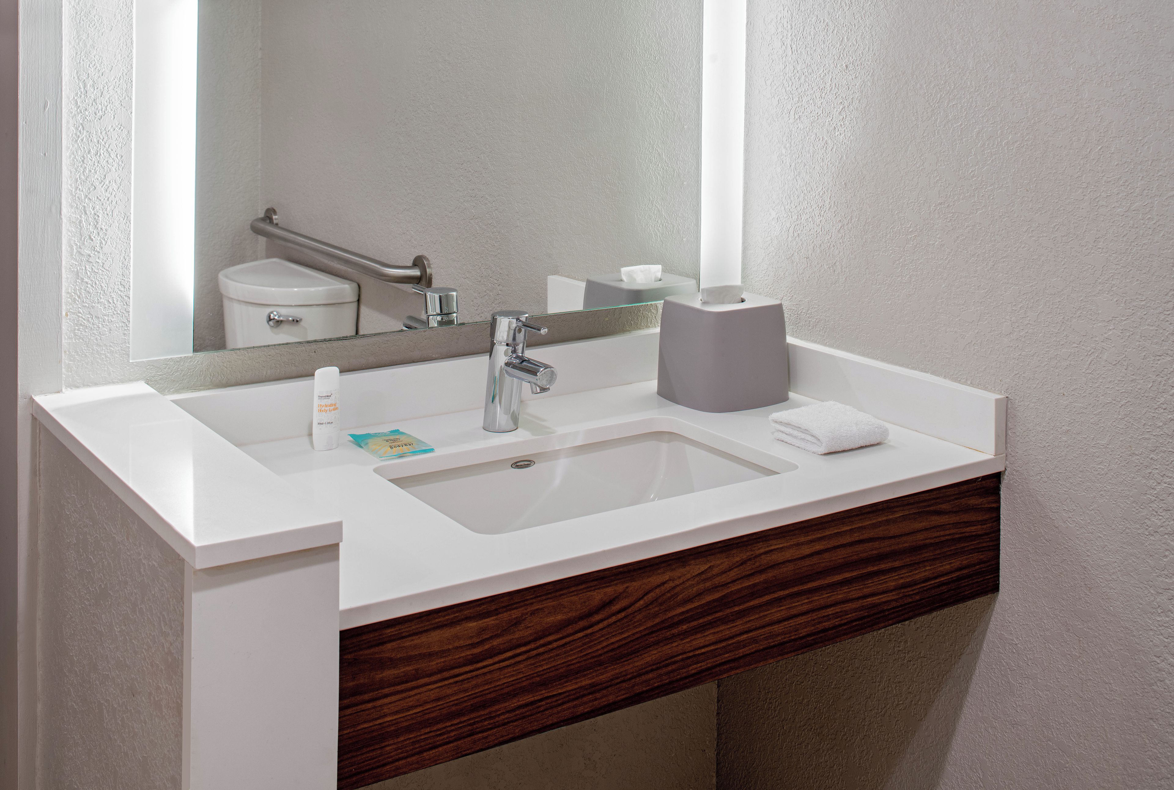 Ein Badezimmer mit einem weißen Waschbecken, einem Spiegel, einem Handtuch und einer Toilette.