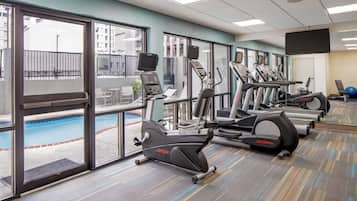 A gym with exercise equipment, a pool, and large windows.