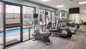 A gym with treadmills, elliptical machines, and a pool area visible through large windows. - Holiday Inn Express New Orleans Downtown by IHG (New Orleans)