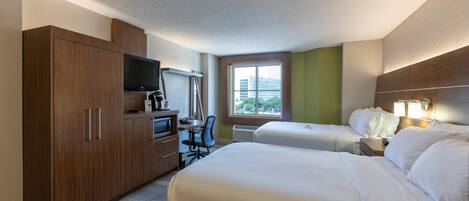 A hotel room with two beds, a desk with a computer, a TV, and a wardrobe.