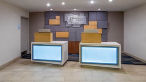 A reception area with two reception desks, a wall-mounted sign for Holiday Inn Express, and a tiled floor. - Holiday Inn Express New Orleans Downtown by IHG (New Orleans)