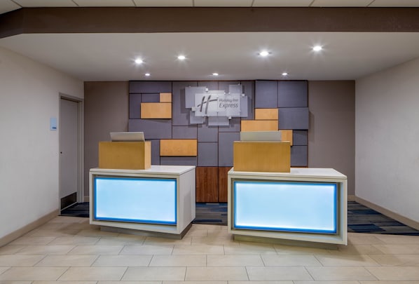 Ett receptionsområde med två receptionsdiskar, en väggmonterad skylt för Holiday Inn Express och ett klinkergolv.