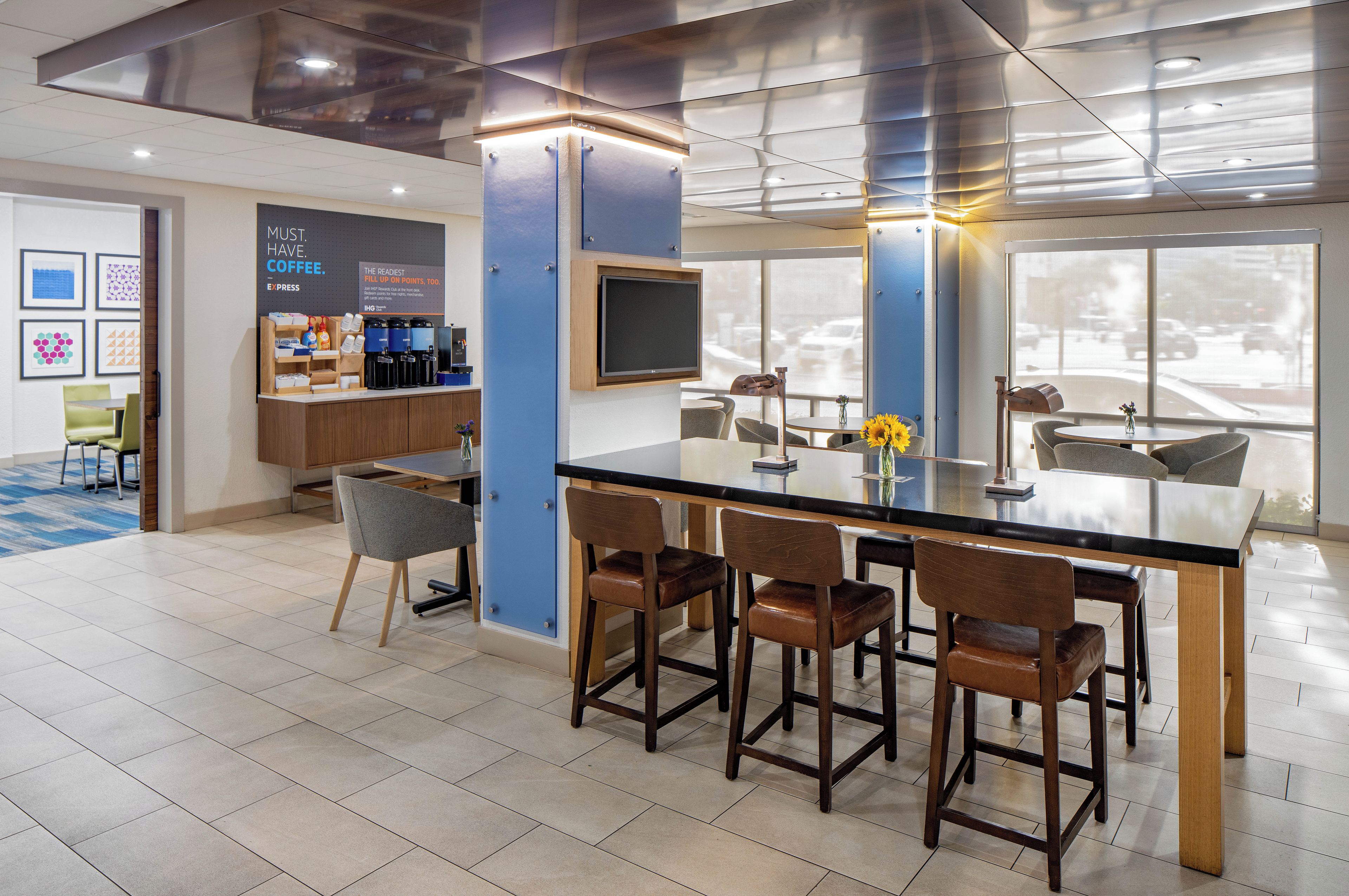 Una zona de bar moderna con una mesa de vidrio, taburetes y una estación de café.