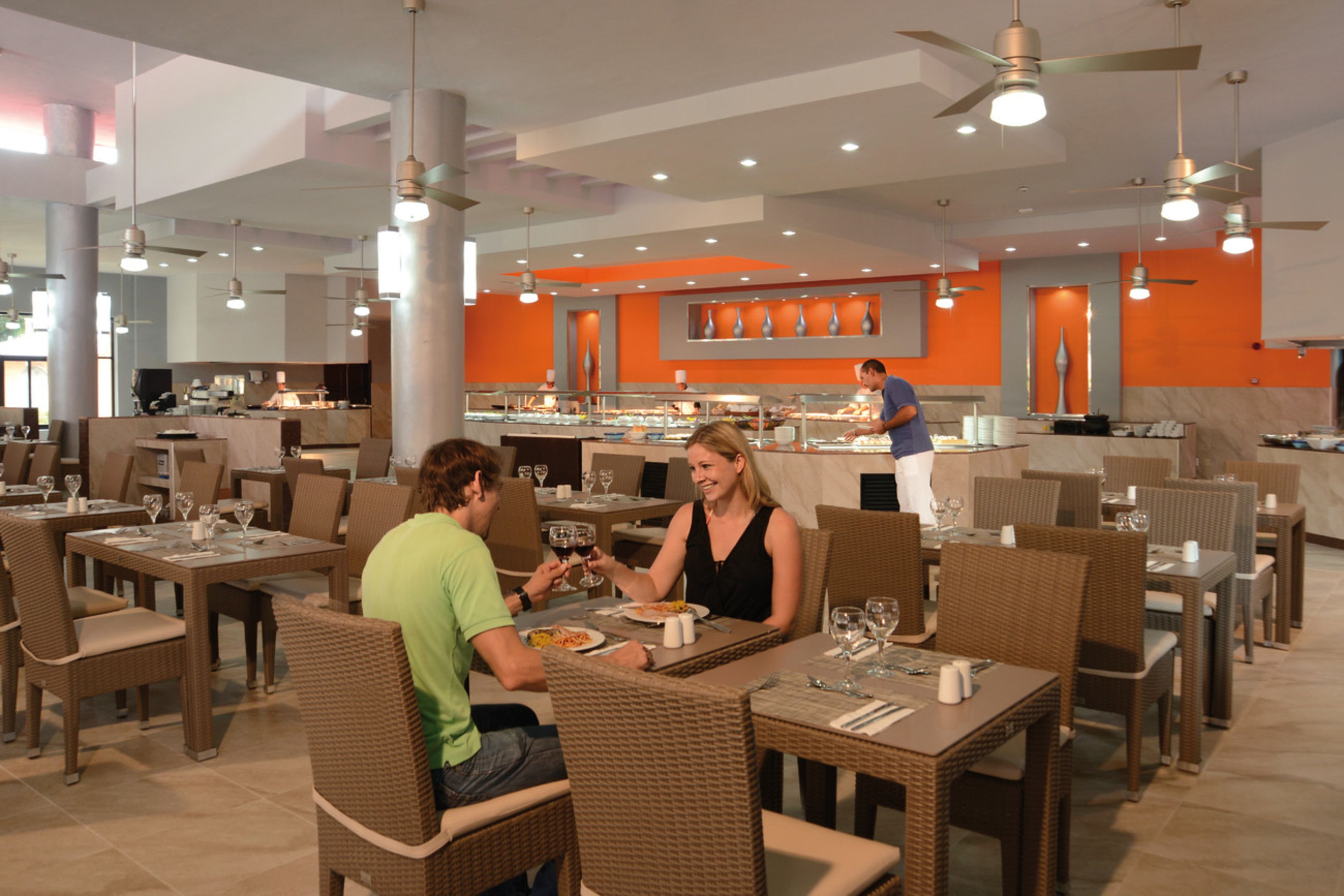 A restaurant with wicker chairs and tables, a buffet area, and a ceiling fan.