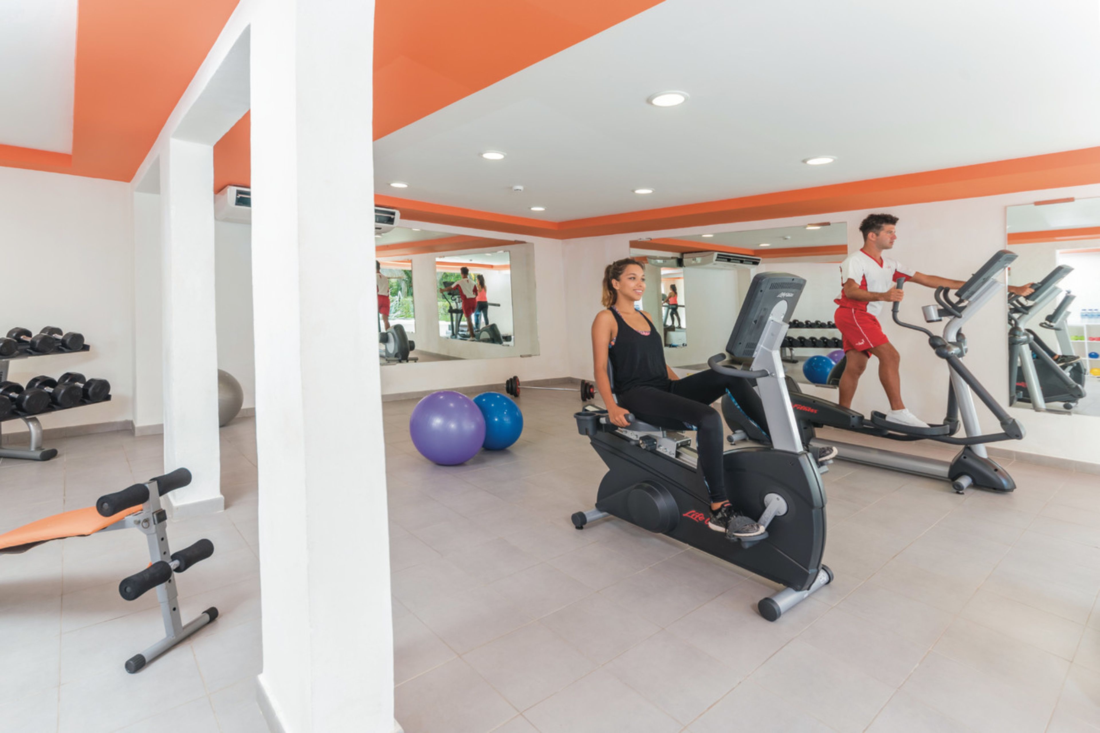 Una palestra con attrezzature per esercizi, una panca e uno specchio.