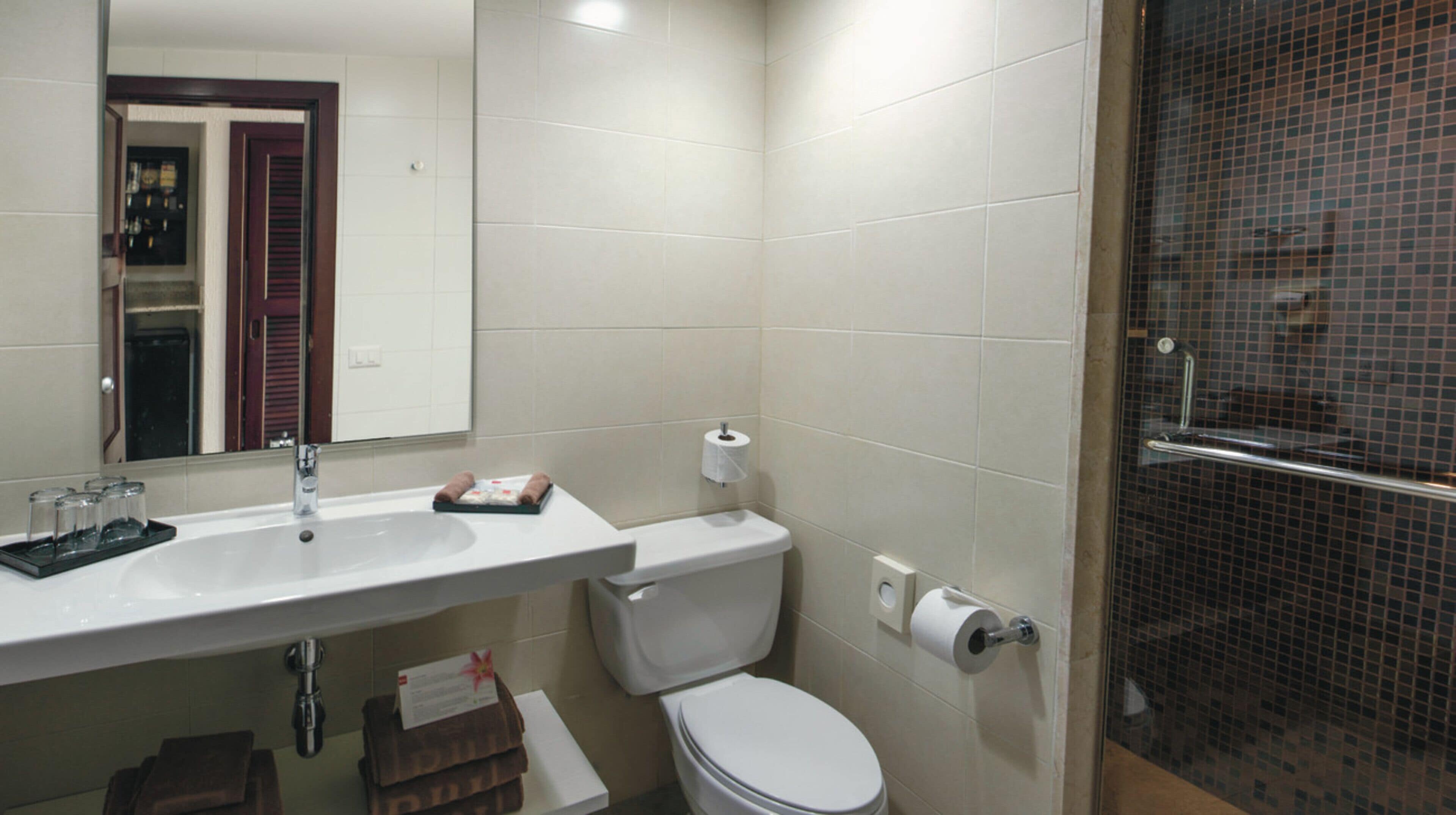 A bathroom with a white sink, toilet, and a shower area.
