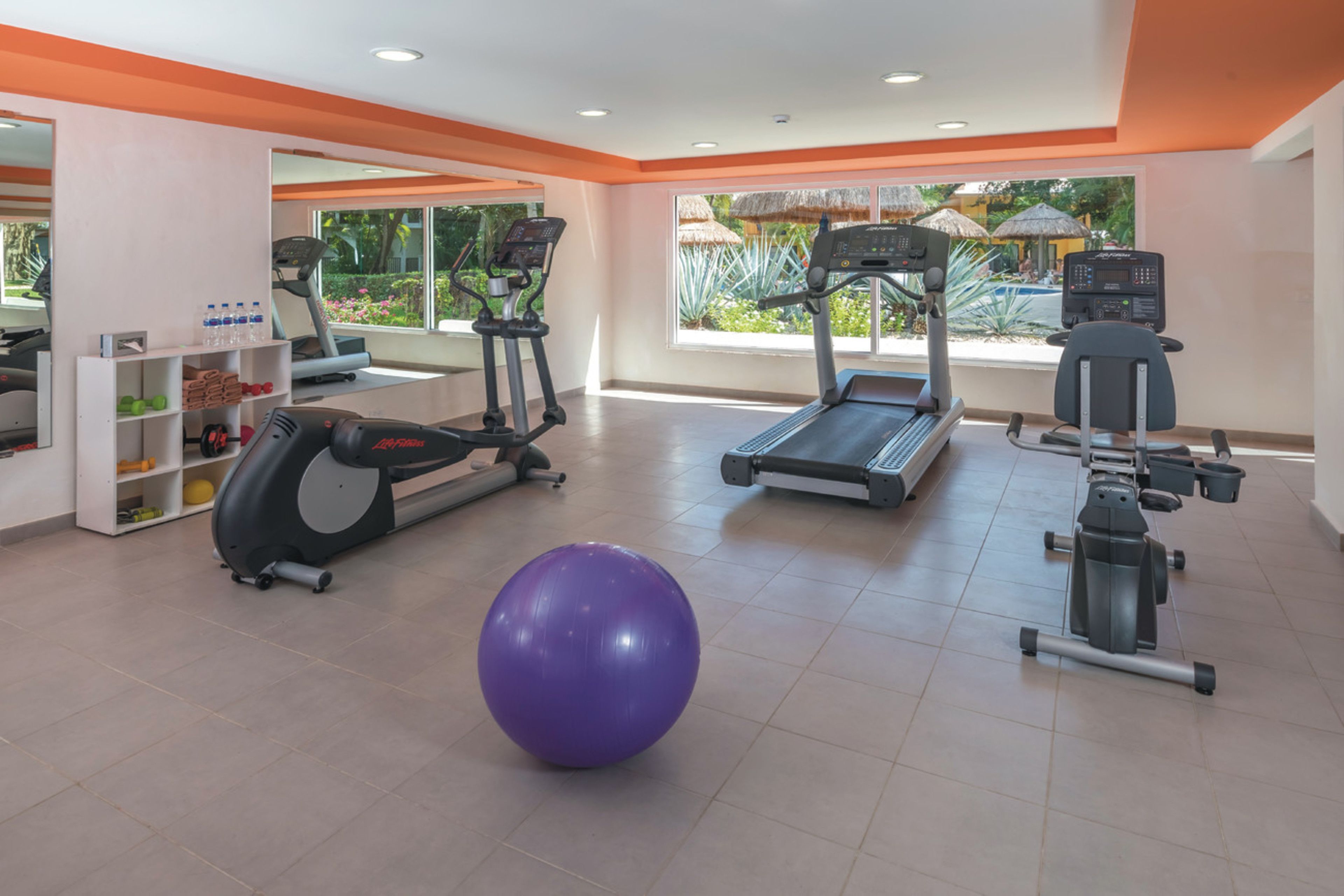 Ein Fitnessstudio mit Laufbändern, Crosstrainern und einem violetten Übungsball.