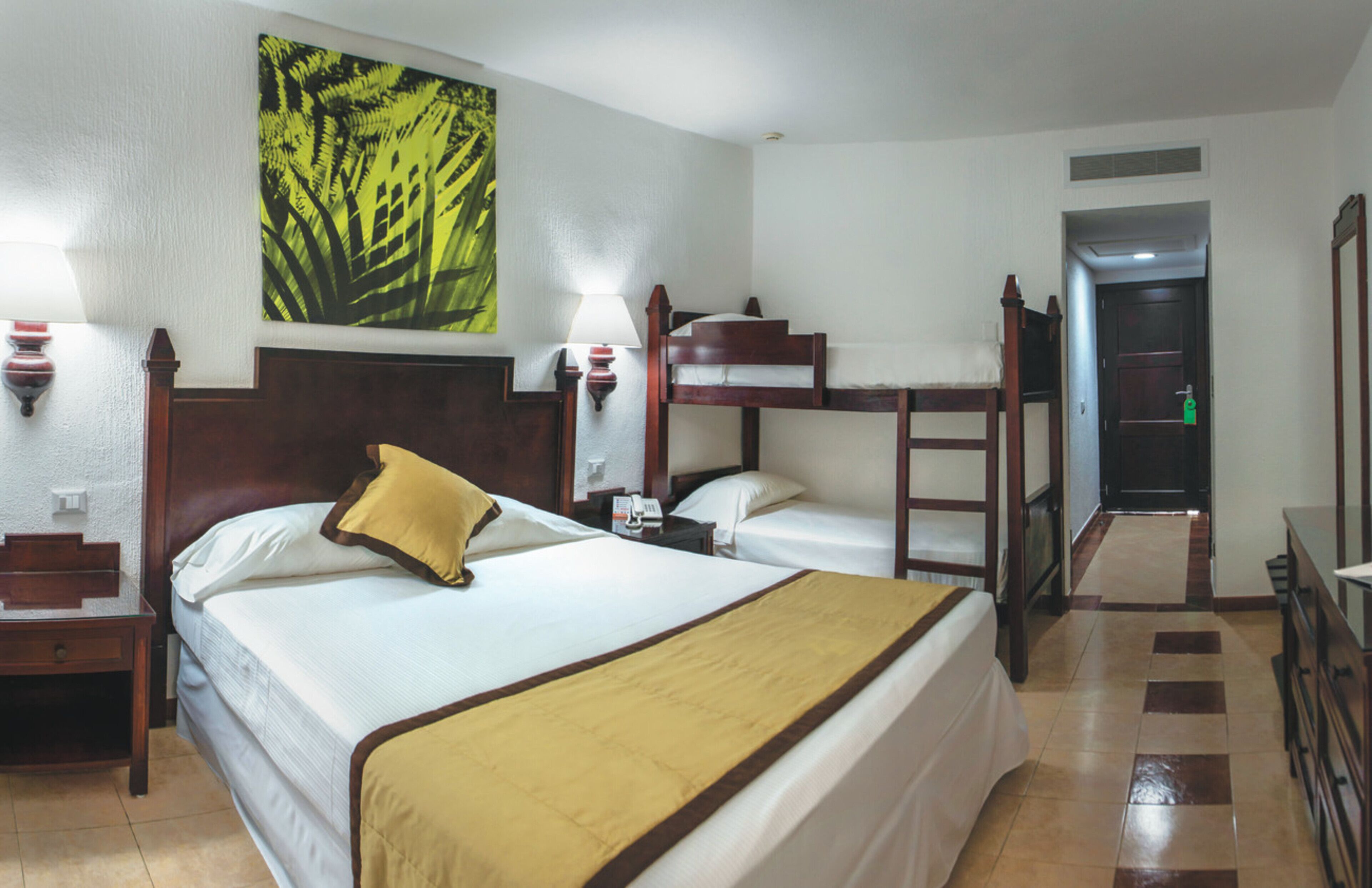 A hotel room with two beds, a bedside table with a lamp, a telephone, and a painting on the wall.