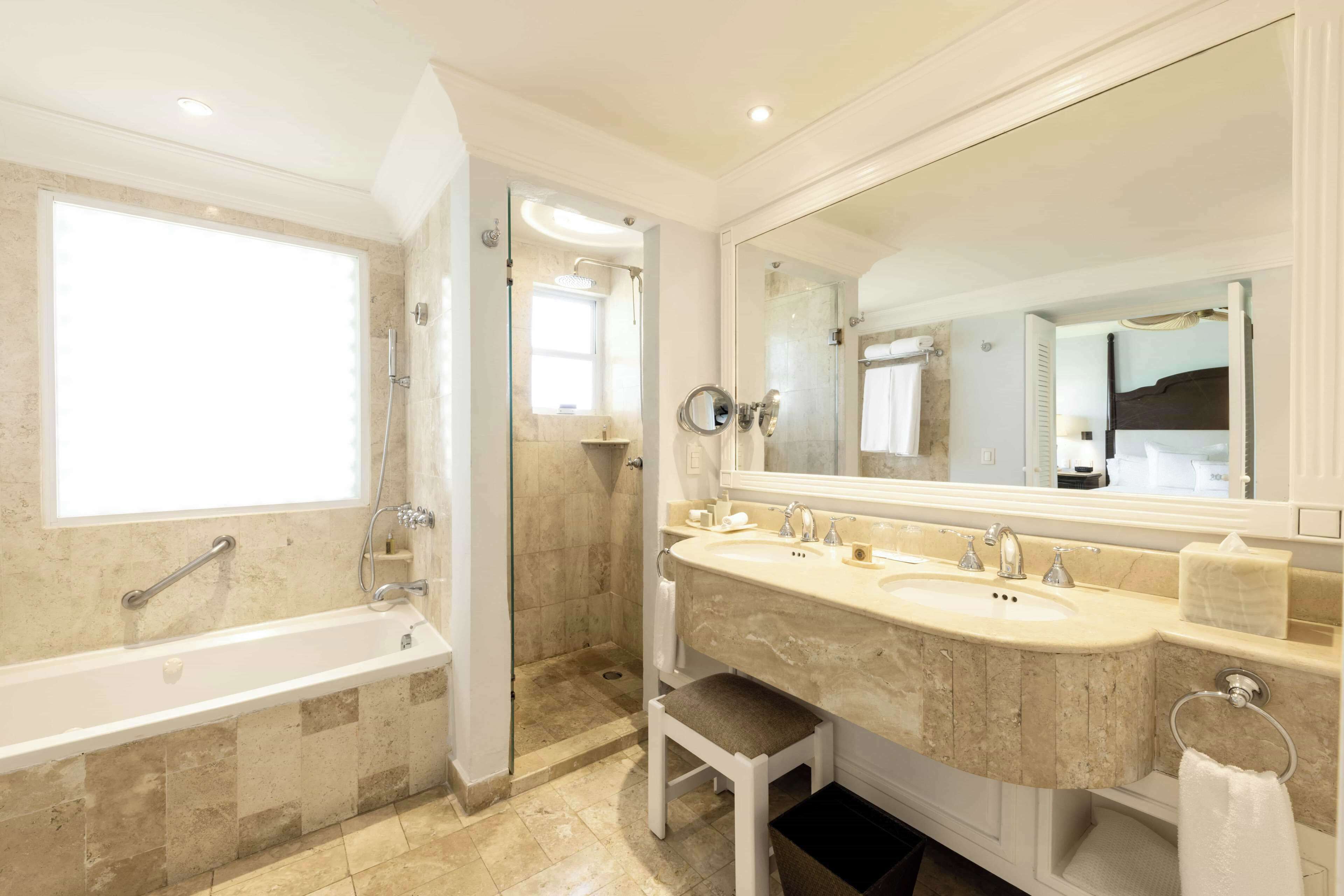 A bathroom with a bathtub, two sinks, a large mirror, and a shower.