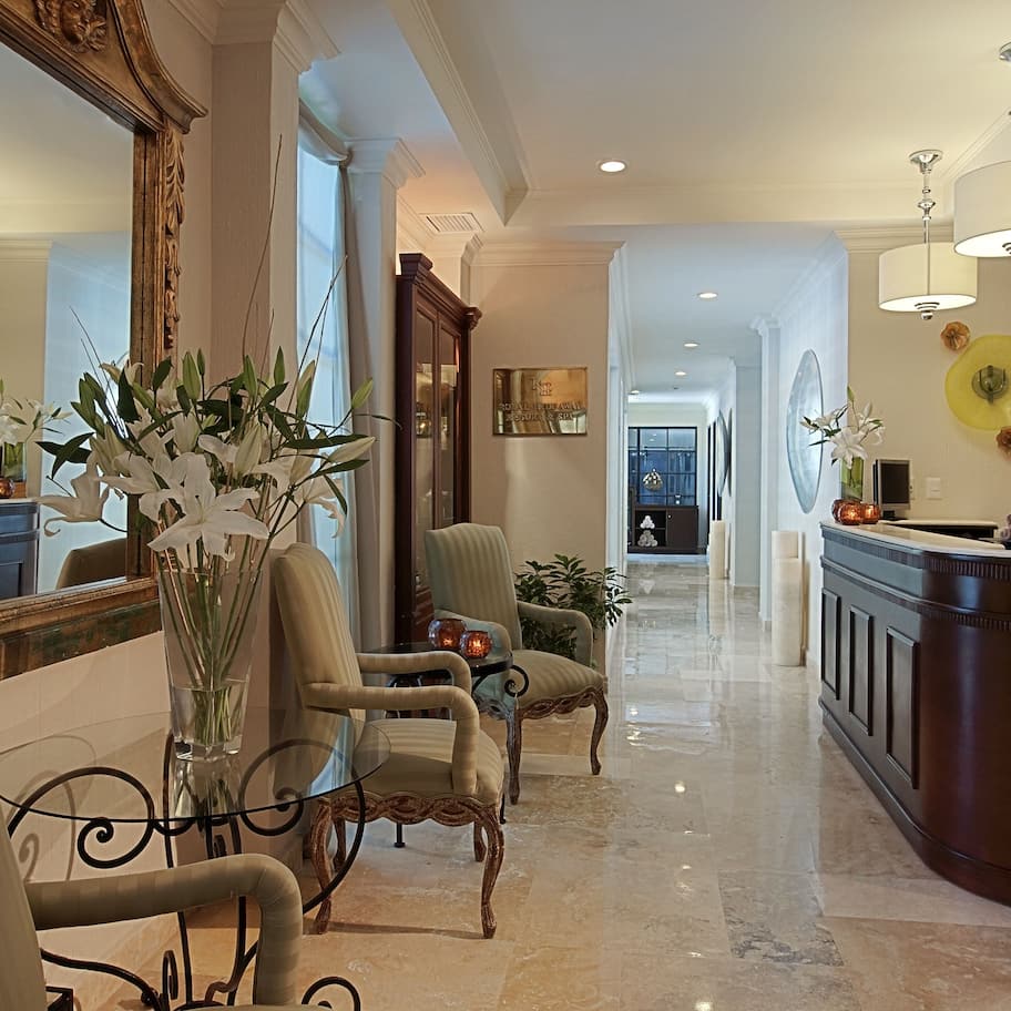 A spacious hallway with a marble floor, a reception desk, and a large mirror.
