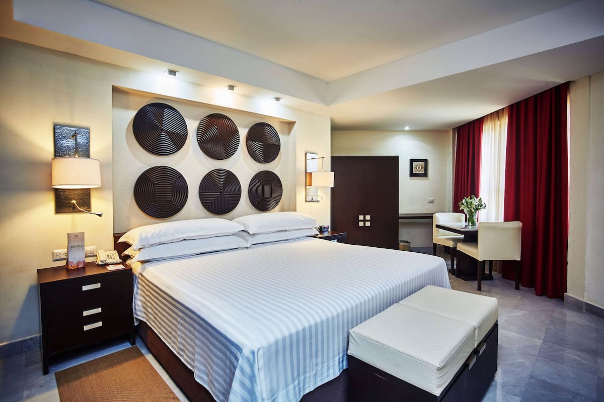 A hotel room with a large bed, bedside tables, a desk, and a chair.
