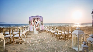 A beach wedding setup with a canopy, chairs, and lanterns.