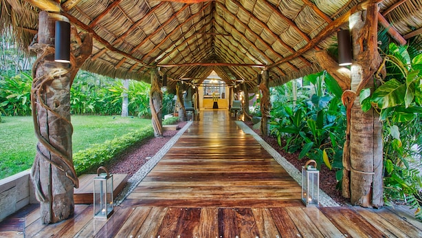 A wooden pathway leading to a thatched-roof structure surrounded by lush greenery. - Occidental Nuevo Vallarta - All Inclusive (Nuevo Nayarit)